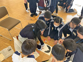 福笑いをする留学生と見守る小学生たち